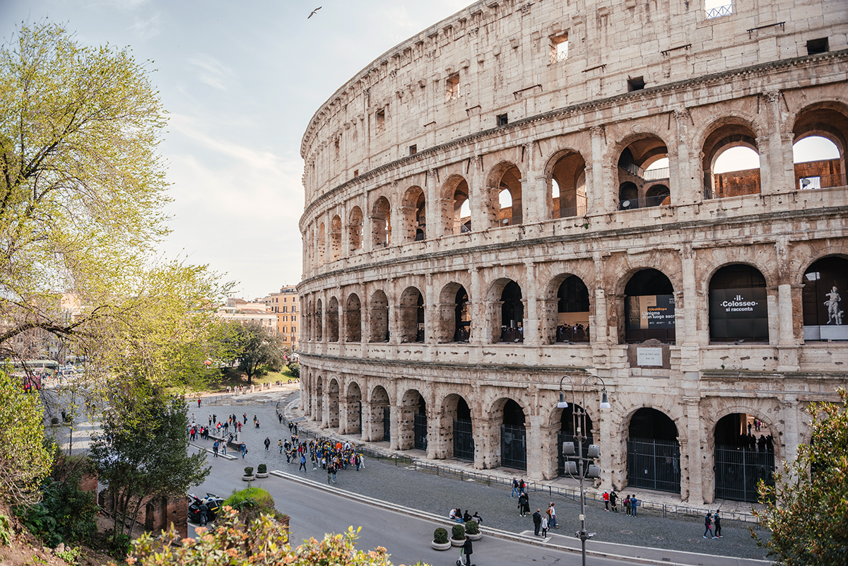Exterior view of the Colosseum in warm daylight with visitors below